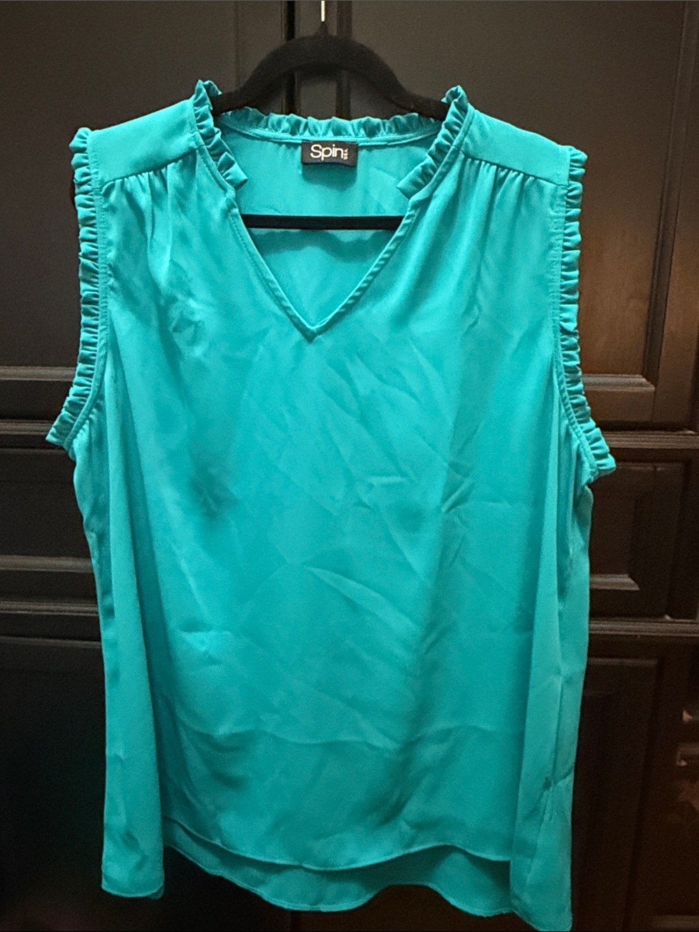 Teal sleeveless top with ruffle trim.
